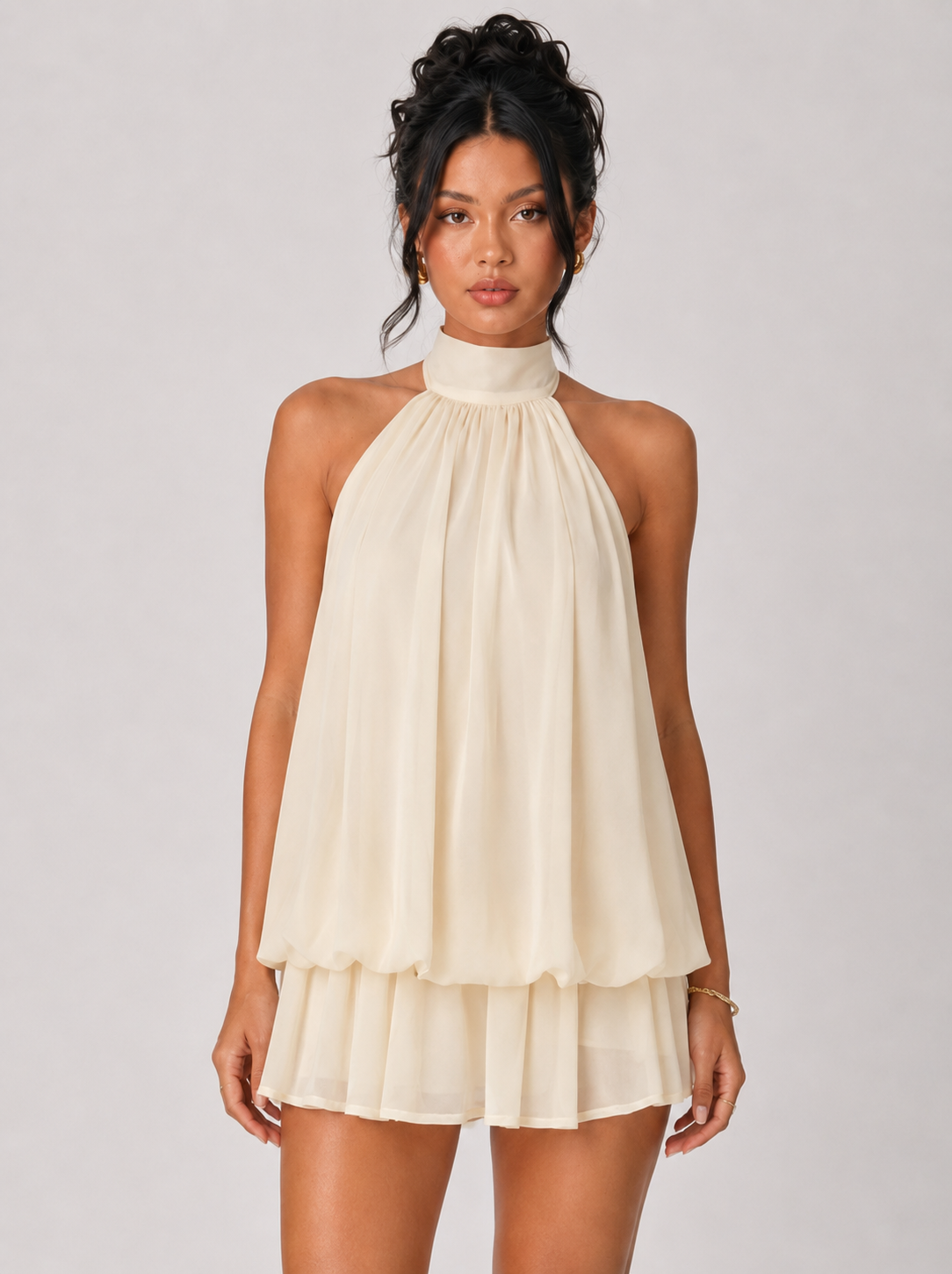 Woman wearing a beige halter neck dress on a plain background