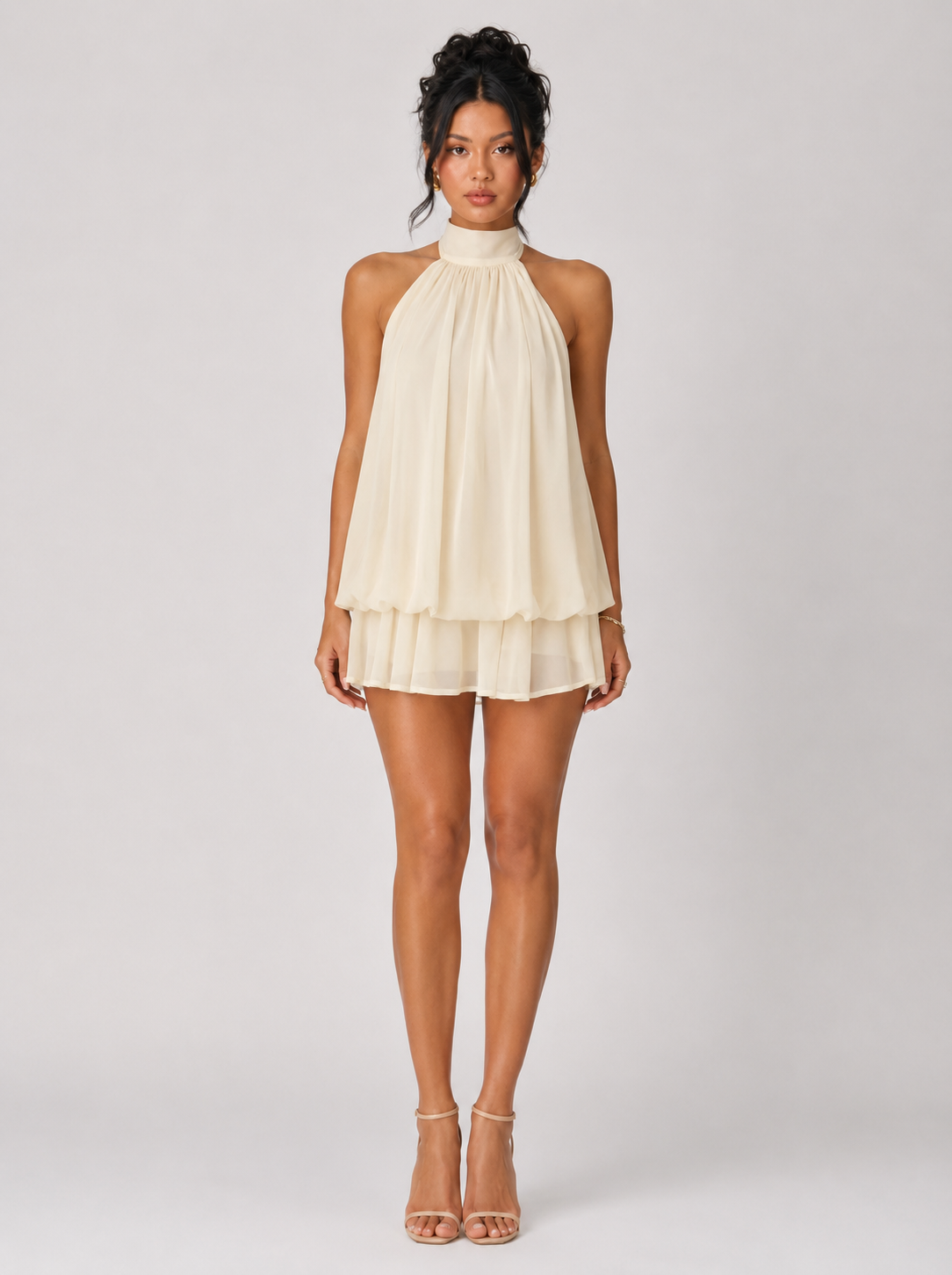 Woman wearing a beige halter neck dress on a white background