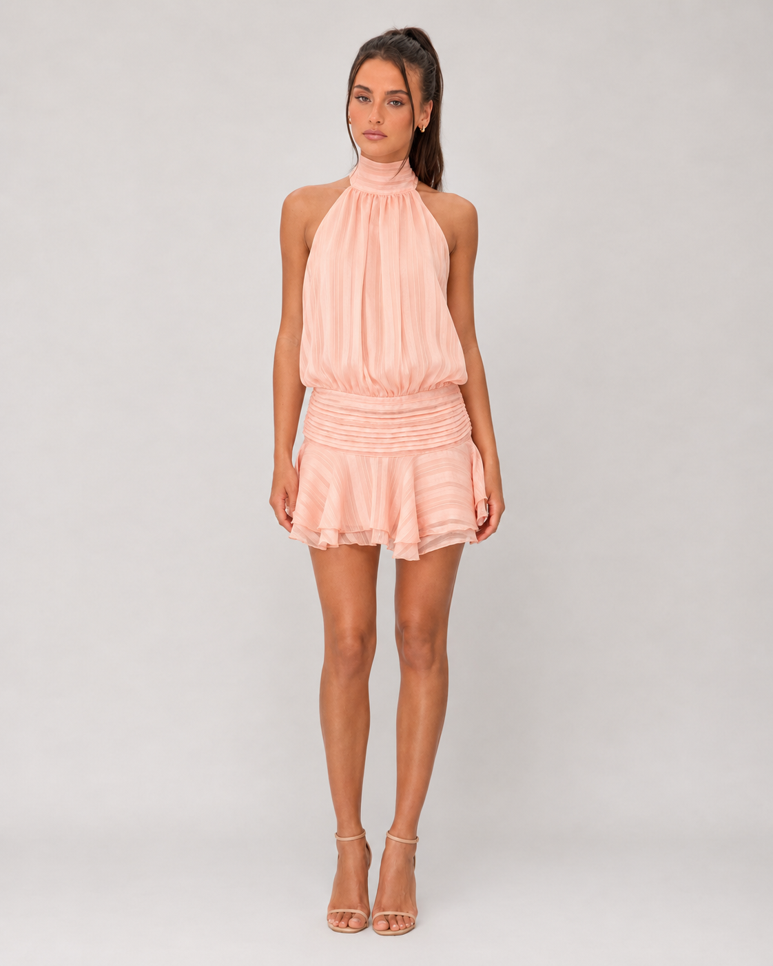 Woman wearing a pink halter top and shorts set on a gray background