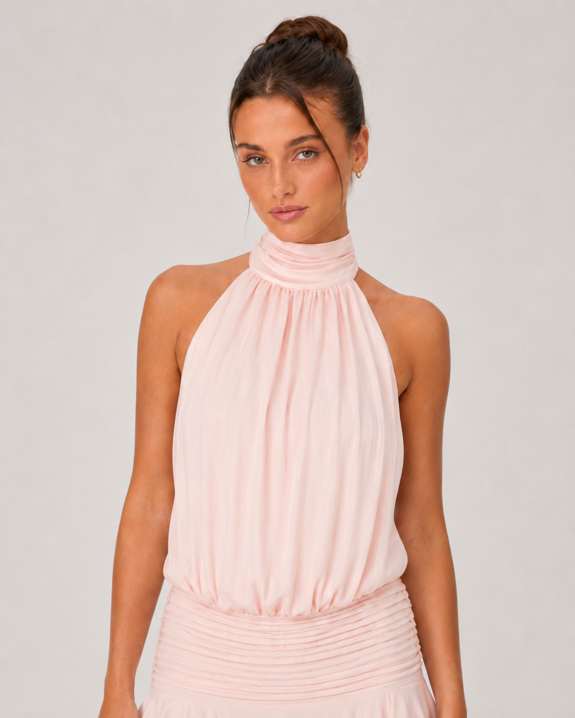 Woman wearing a pink halter neck dress against a plain background
