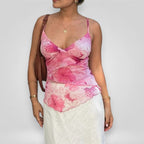 Woman wearing a pink floral top and white skirt against a plain background